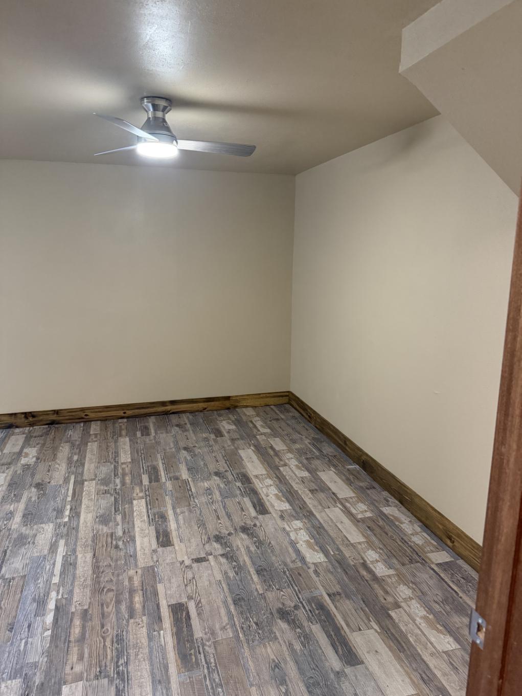 Finished drywall walls with wood trim layouts and ceiling fan with light fixture